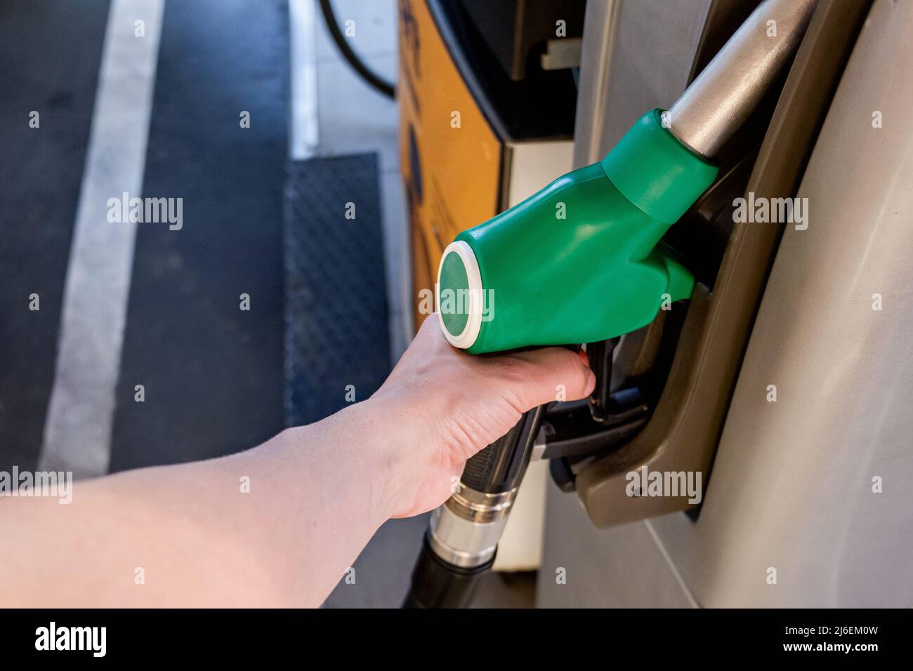 Hand eines jungen Mannes, der das Auto an der Tankstelle betankt. Konzept des Kraftstoffverbrauchs (Benzin, Diesel) in Verbrennungsmotoren, Luftverschmutzung und Umweltgesundheit. Stockfoto