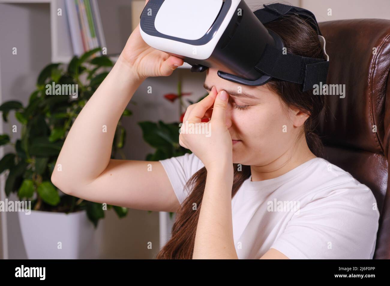 Eine Frau in einer Virtual-Reality-Brille blickt auf einen grauen Hintergrund. Stockfoto