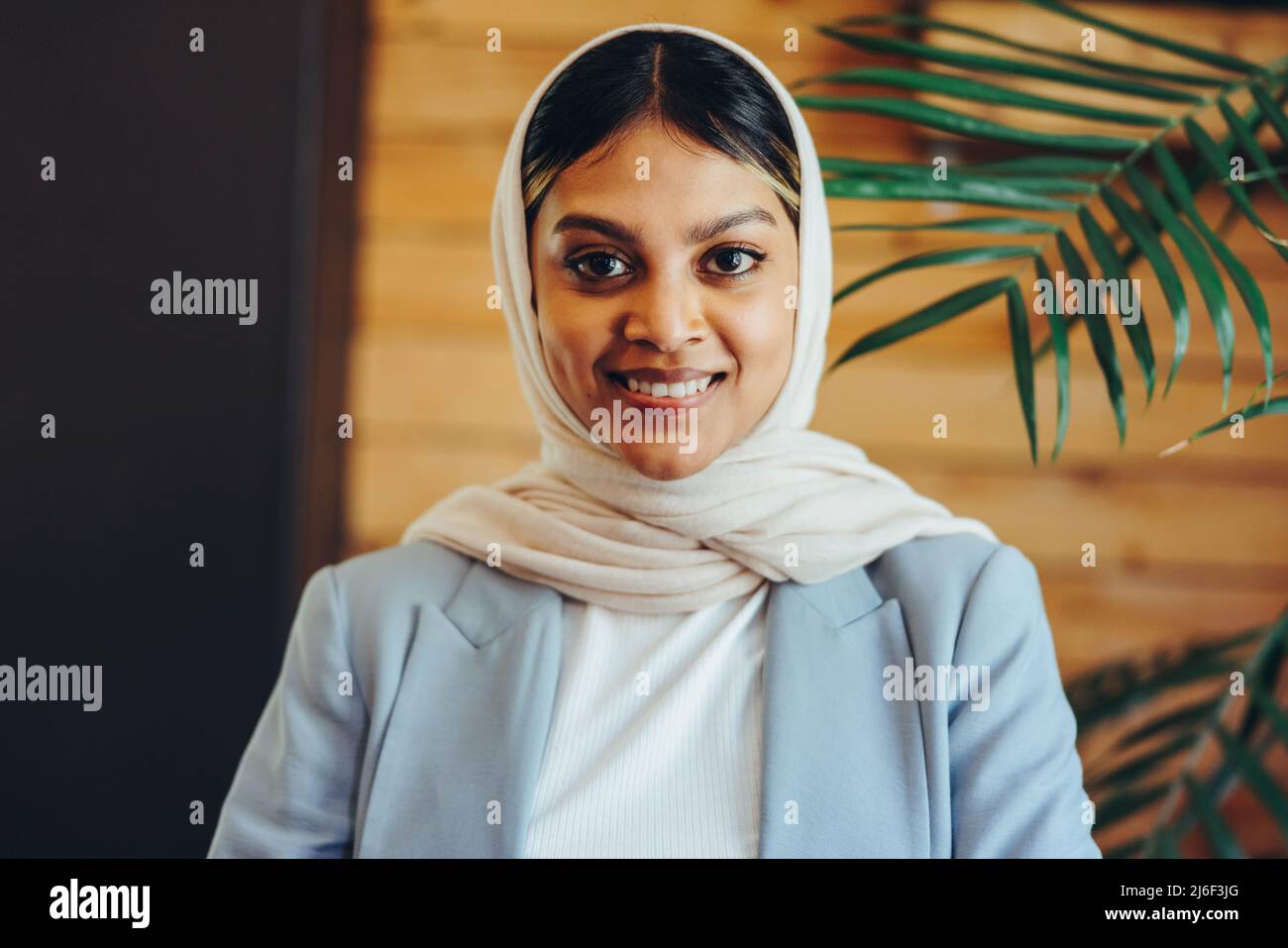 Porträt einer muslimischen Geschäftsfrau, die die Kamera anschaut, während sie einen Hijab trägt. Glückliche Unternehmerin, die an einem integrativen Arbeitsplatz arbeitet. Stockfoto Porträt einer muslimischen Geschäftsfrau, die die Kamera anschaut, während sie einen Hijab trägt. Glückliche Unternehmerin, die an einem integrativen Arbeitsplatz arbeitet. Stockfoto