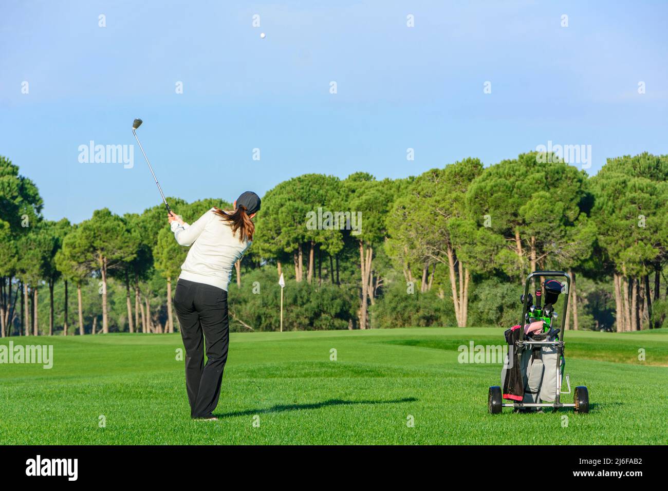 Golfspielerin trifft Ball auf Fairway Stockfoto