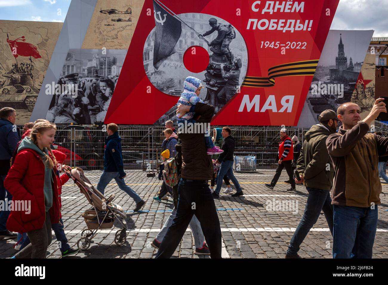 Moskau, Russland. Am 1.. Mai gehen 2022 Menschen auf dem Roten Platz vor dem Hintergrund der festlichen Dekoration, die einer Militärparade auf dem Roten Platz zum 77.. Jahrestag des Sieges im Zweiten Weltkrieg gewidmet ist. Tag des Sieges, im Zentrum von Moskau, Russland Stockfoto