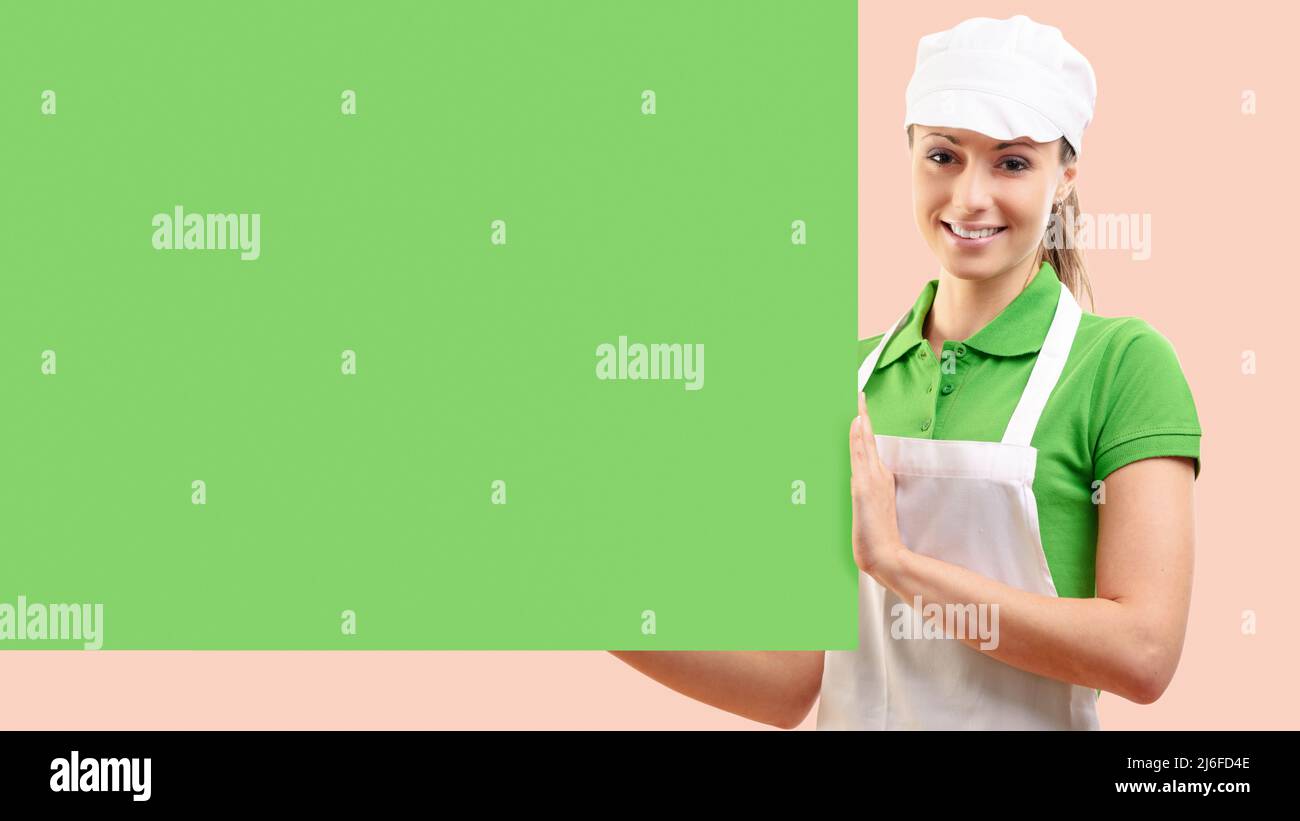 Weibliche Lebensmittelladen Assistentin mit einem grünen Schild, Lebensmitteleinkaufkonzept Stockfoto