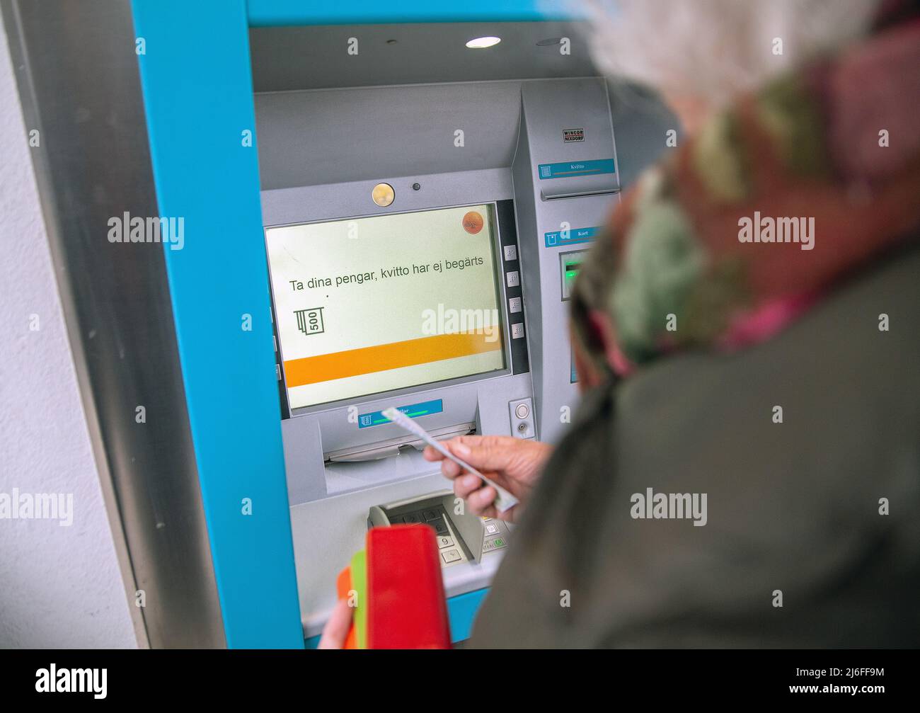 Schwedische Frau cassh Geld von automatisieren Bank Kasse in Malmkoping Schweden Stockfoto