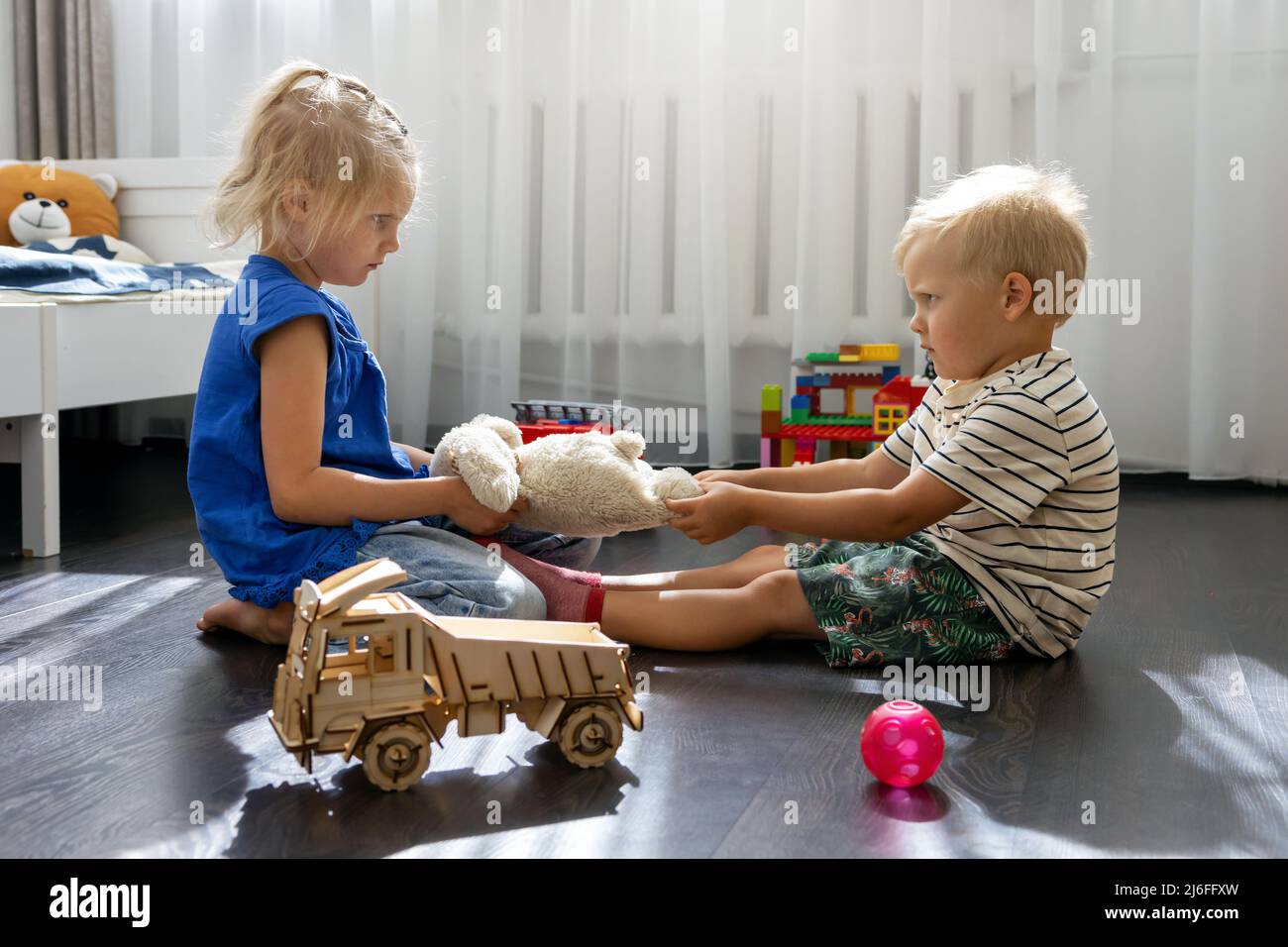 Kinder kämpfen um ein Spielzeug. Konflikt zwischen Schwester und Bruder. Geschwisterbeziehungen Stockfoto