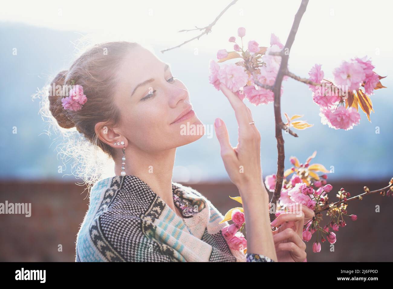Weiße Frau im Sonnenlicht hält Kirschbaumblüte im Frühling, Weiblichkeit Stockfoto