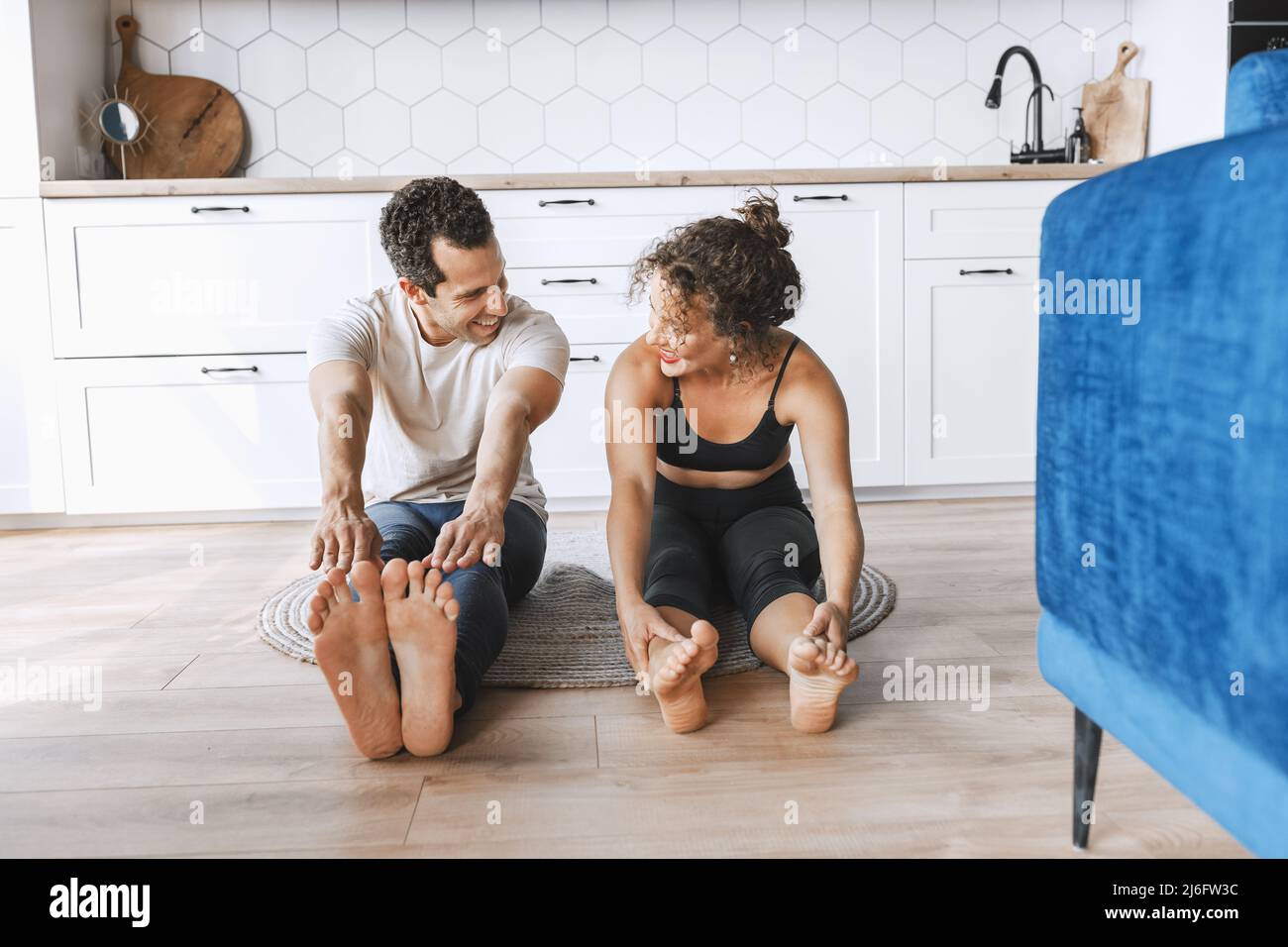 Lächelndes junges sportliches Paar, das Yoga-Unterricht praktiziert, dabei nach oben schauende Hundeübung macht, Urdhva mukha shvanasana Pose, Workout, Indoor voller Länge Stockfoto