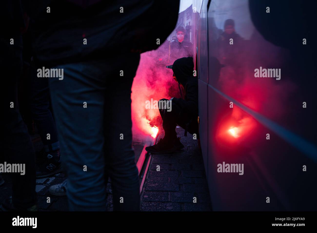 01. Mai 2022, Hessen, Frankfurt/Main: Ein Teilnehmer sitzt im Radbrunnen eines Busses, während neben ihm Pyrotechnik entzündet wurde. Am Abend demonstrierte in Frankfurt am Main ein Bündnis mehrerer linker Organisationen. Foto: Hannes P. Albert/dpa Stockfoto