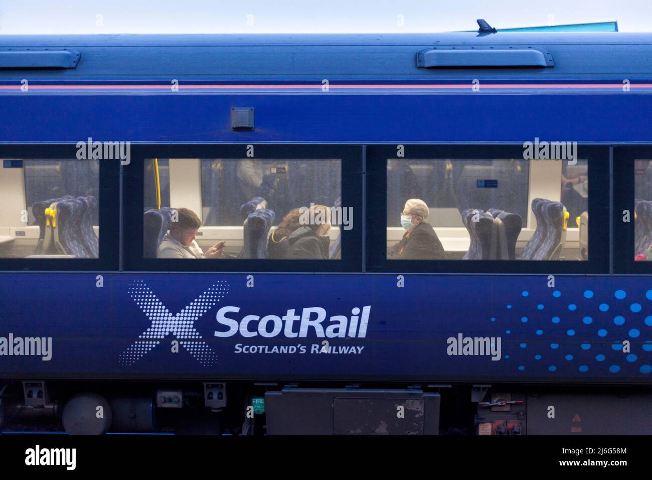 Bahnreisende von ScotRail in einem Zug der Klasse 170 mit dem Scotrail-Logo trägt einer der Passagiere eine Gesichtsmaske Stockfoto