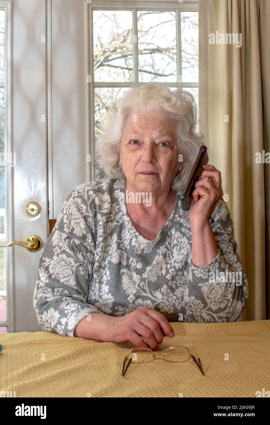 Ältere Frau bekommt schockierende Nachrichten auf ihr Handy Stockfoto