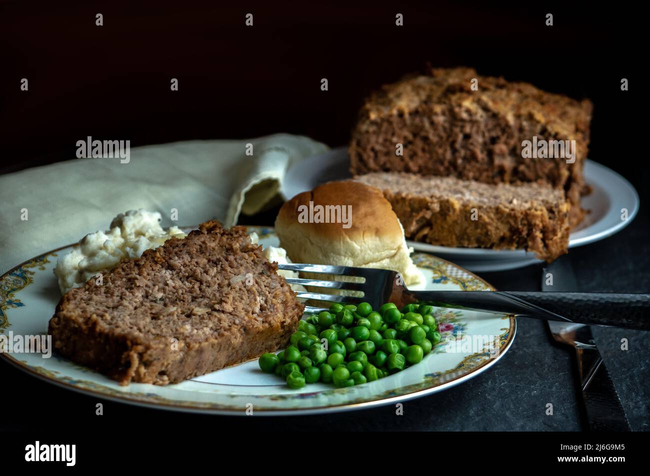 Hausgemachtes Fleisch-Laib-Abendessen mit Kartoffelpüree, grünen Erbsen und einer Rolle für das Abendessen Stockfoto