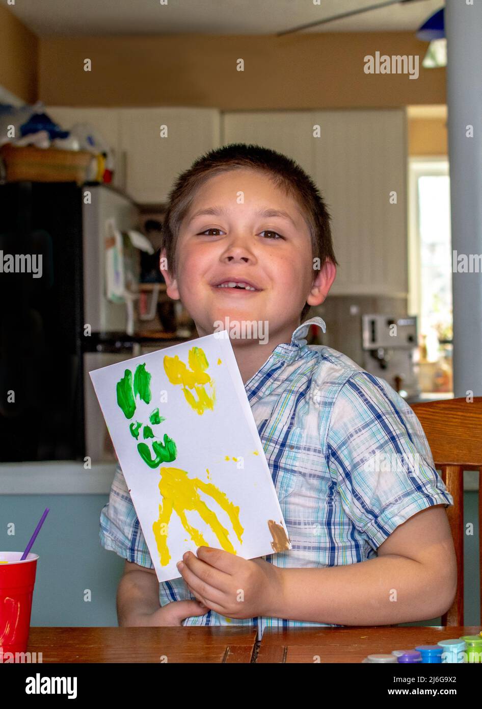 Stolzer kleiner Junge zeigt eine handbemalte Karte, die er gerade gemacht hat Stockfoto