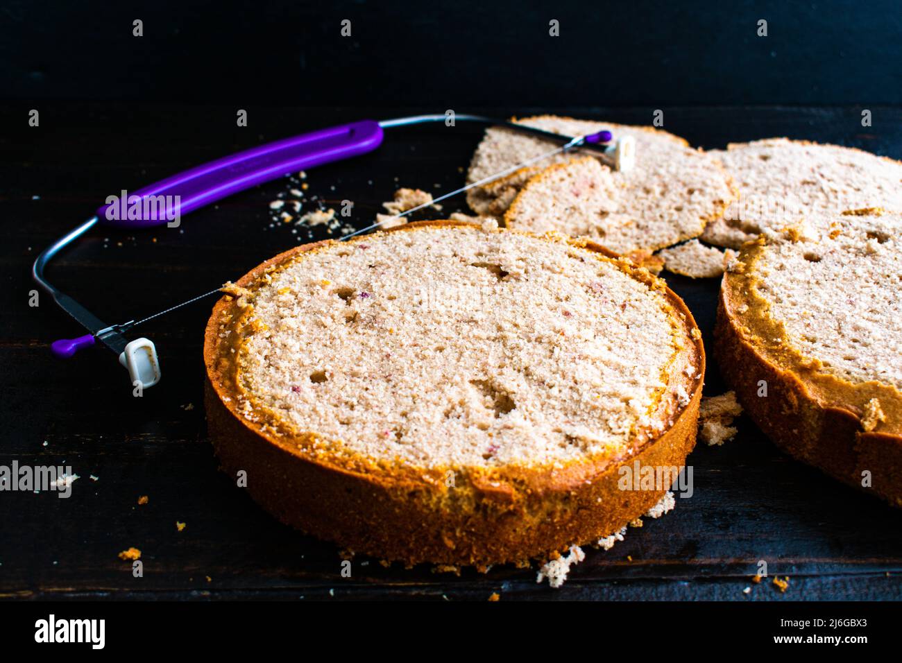 Nivellierung frisch gebackener Erdbeerkuchen: Zwei Kuchen, die gerade mit einer verstellbaren Drahtkuchenwaage geglättet wurden Stockfoto