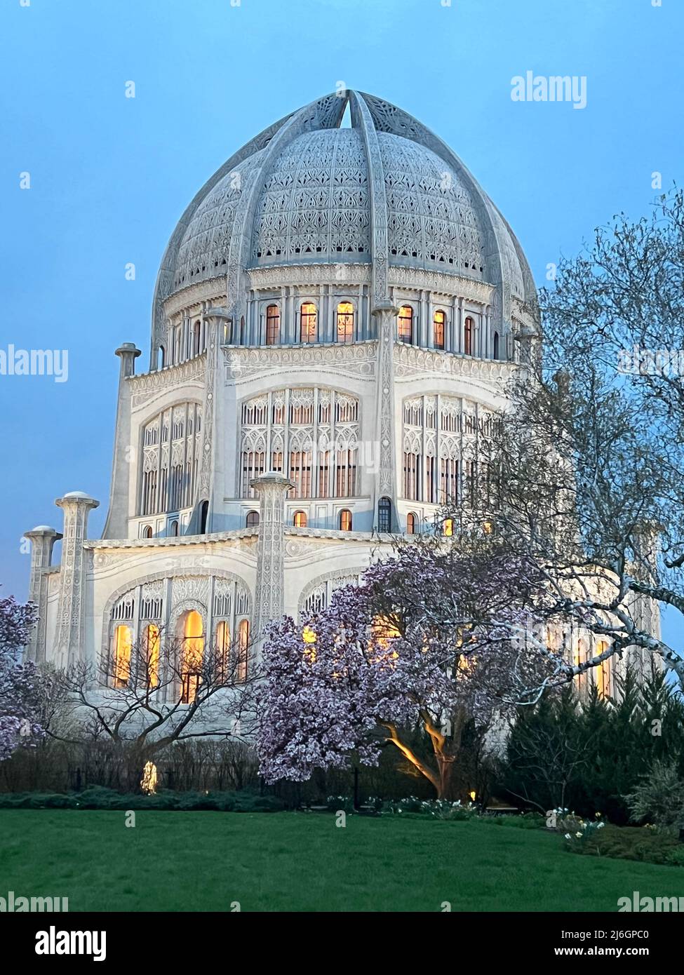 Baha'i House of Worship an einem frühen Frühlingsabend mit blühenden Bäumen in voller Blüte. Der Tempel befindet sich in Wilmette, Illinois. Stockfoto