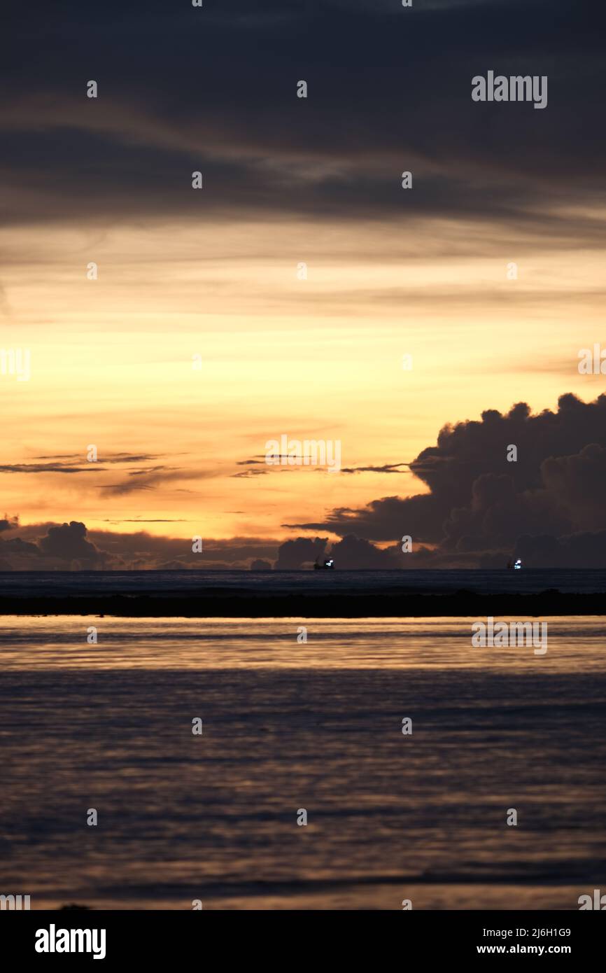 Die Lichter eines entfernten Schiffes werden in einer warmen Luft über einem späten Sonnenuntergang in der Andamanensee stark verzerrt Stockfoto