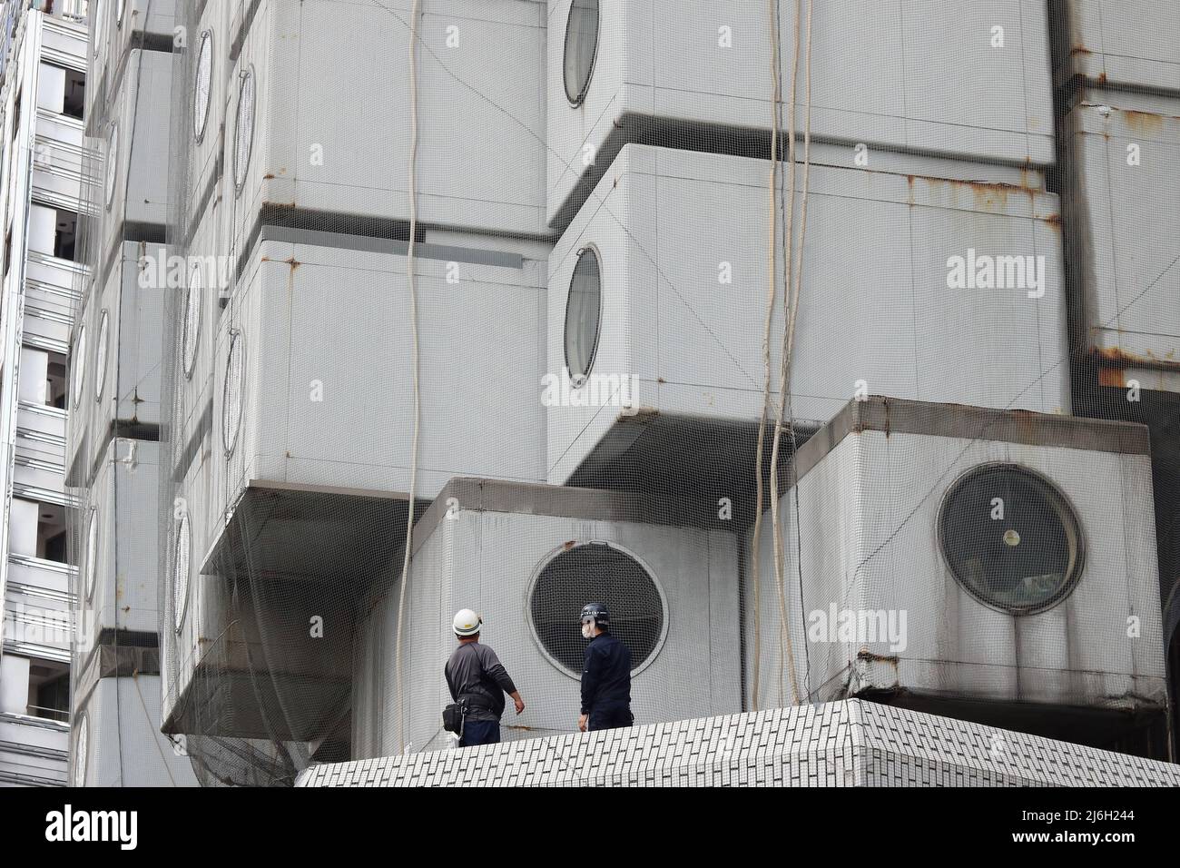 TOKIO, JAPAN – 13. April 2022: Arbeiter am unter dem Abriss stehenden Nakagin Capsule Tower in Tokyos Ginza-Gegend. Stockfoto