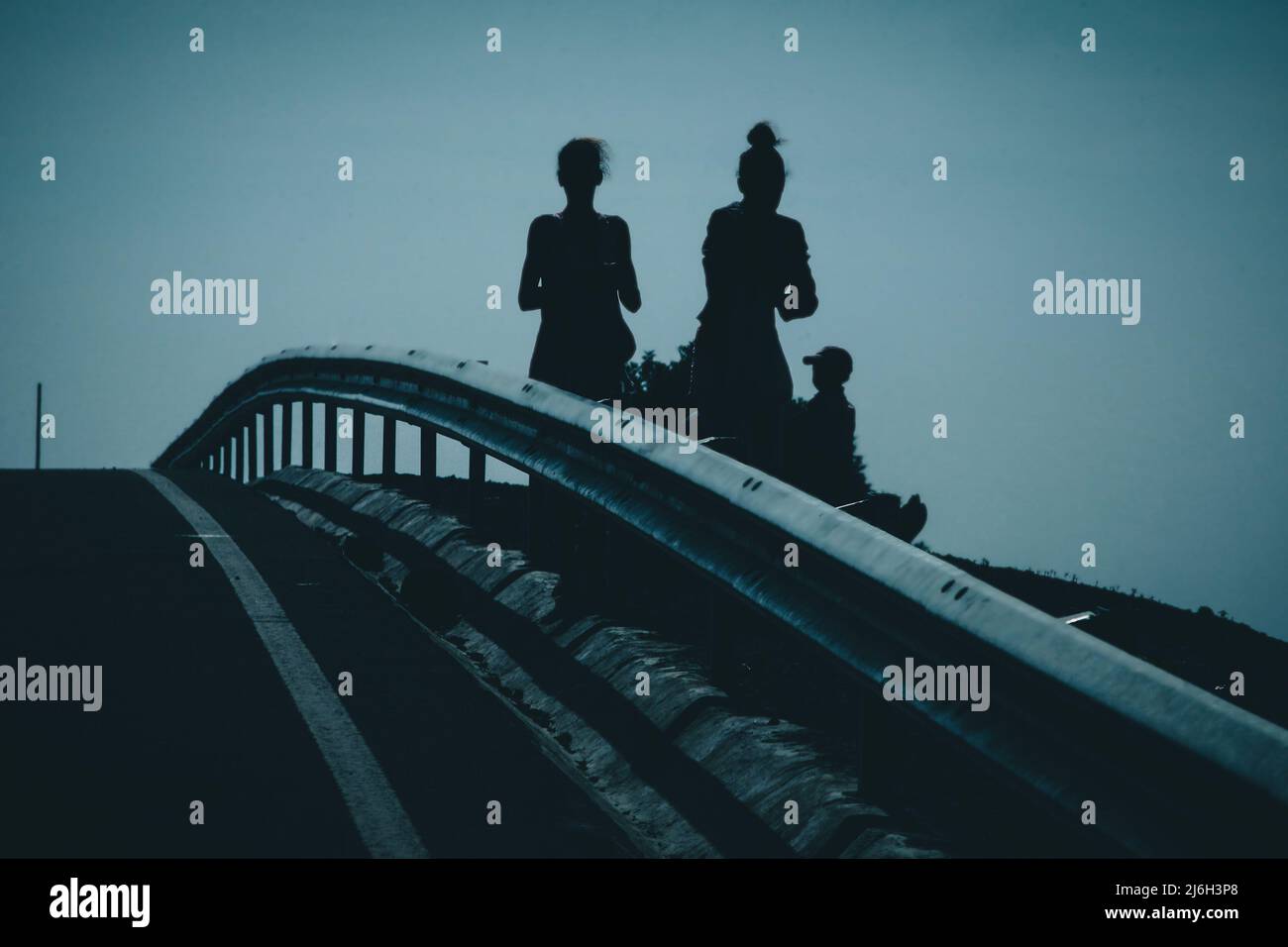 Silhouetten verschiedener Menschen, die neben der Straße stehen und Waren oder Lebensmittel auf den Cabo Verde-Inseln in Afrika verkaufen. Gemeinsamer Blick auf die Länder der Dritten Welt Stockfoto