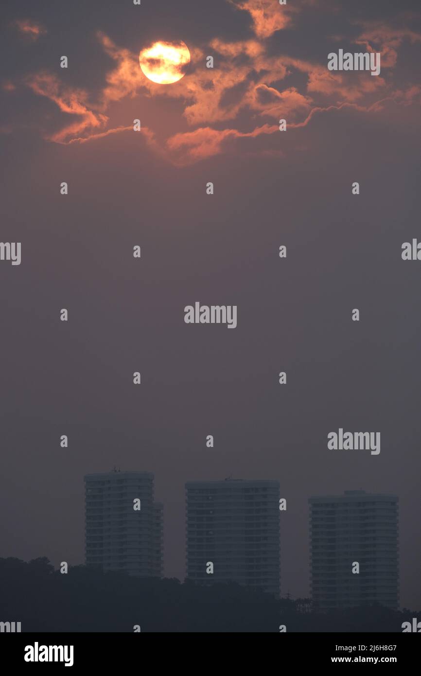 Die Sonne scheint durch schwere Wolken über einem Hügel mit Wohngebäuden Stockfoto Die Sonne scheint durch schwere Wolken über einem Hügel mit Wohngebäuden Stockfoto