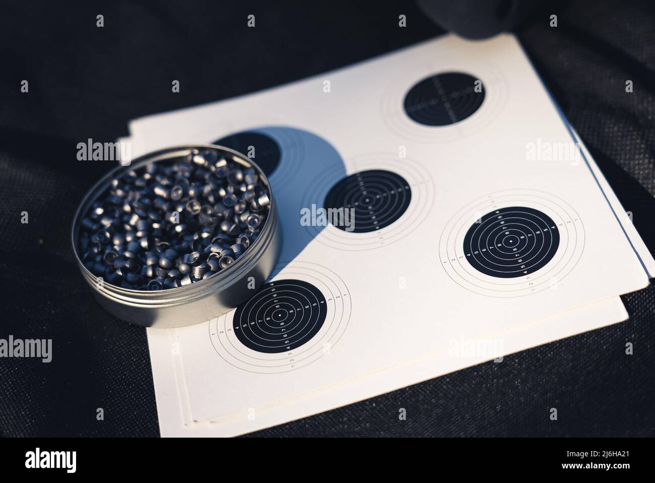 10.03.2021 Warschau, Polen. CO2 Kapsel und Ziel auf einem schwarzen Material flach lag Schuss. Luftgewehrkugeln. Hochwertige Fotos Stockfoto