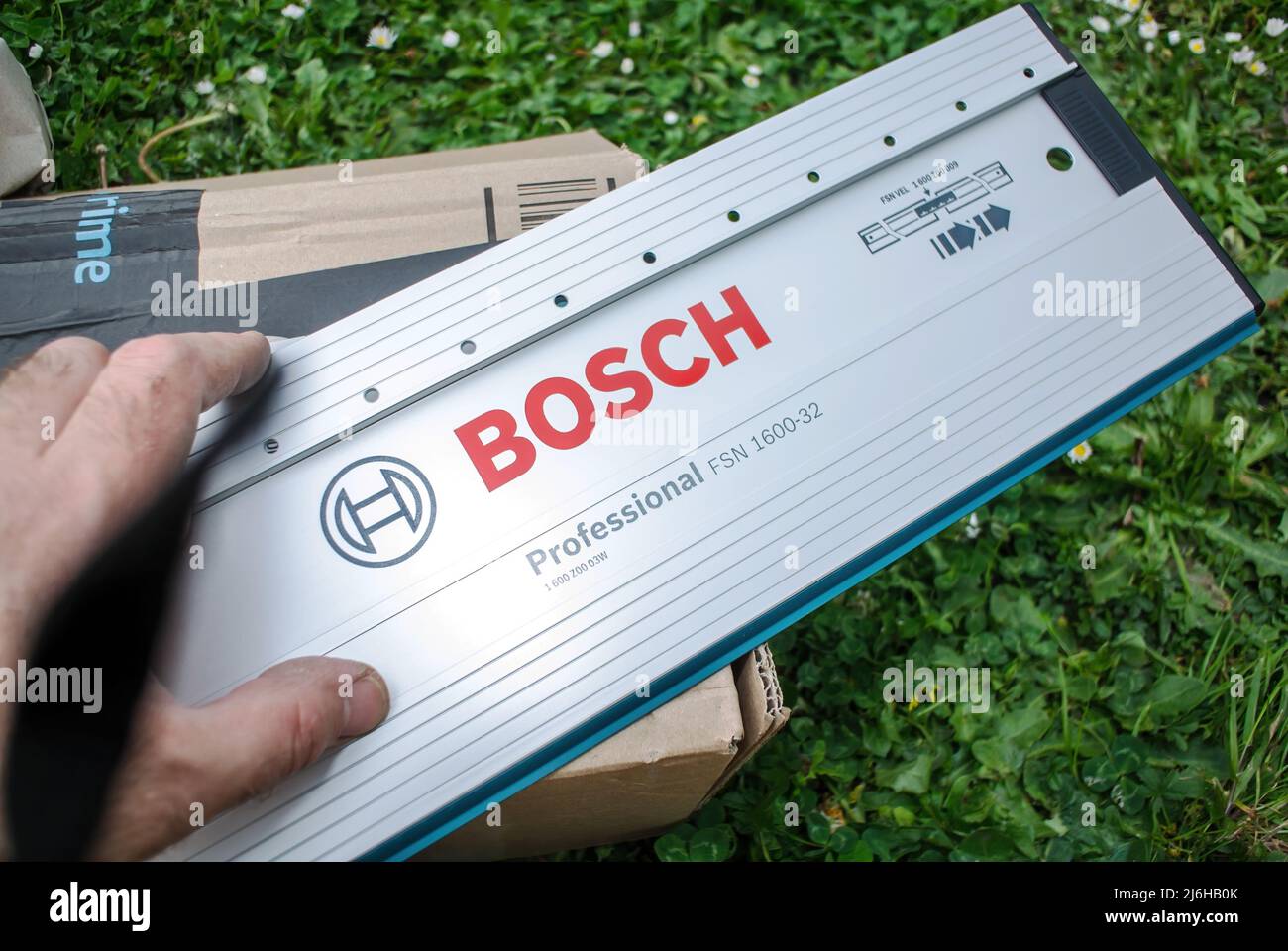 Paris, Frankreich - 29. Apr 2022: Arbeitermännchen zeigt auf die Bosch Professional Führungsschiene mit 32-Loch-Aufbau, 1600 mm langes Modell FSN 1600 32 direkt nach dem Auspacken Stockfoto