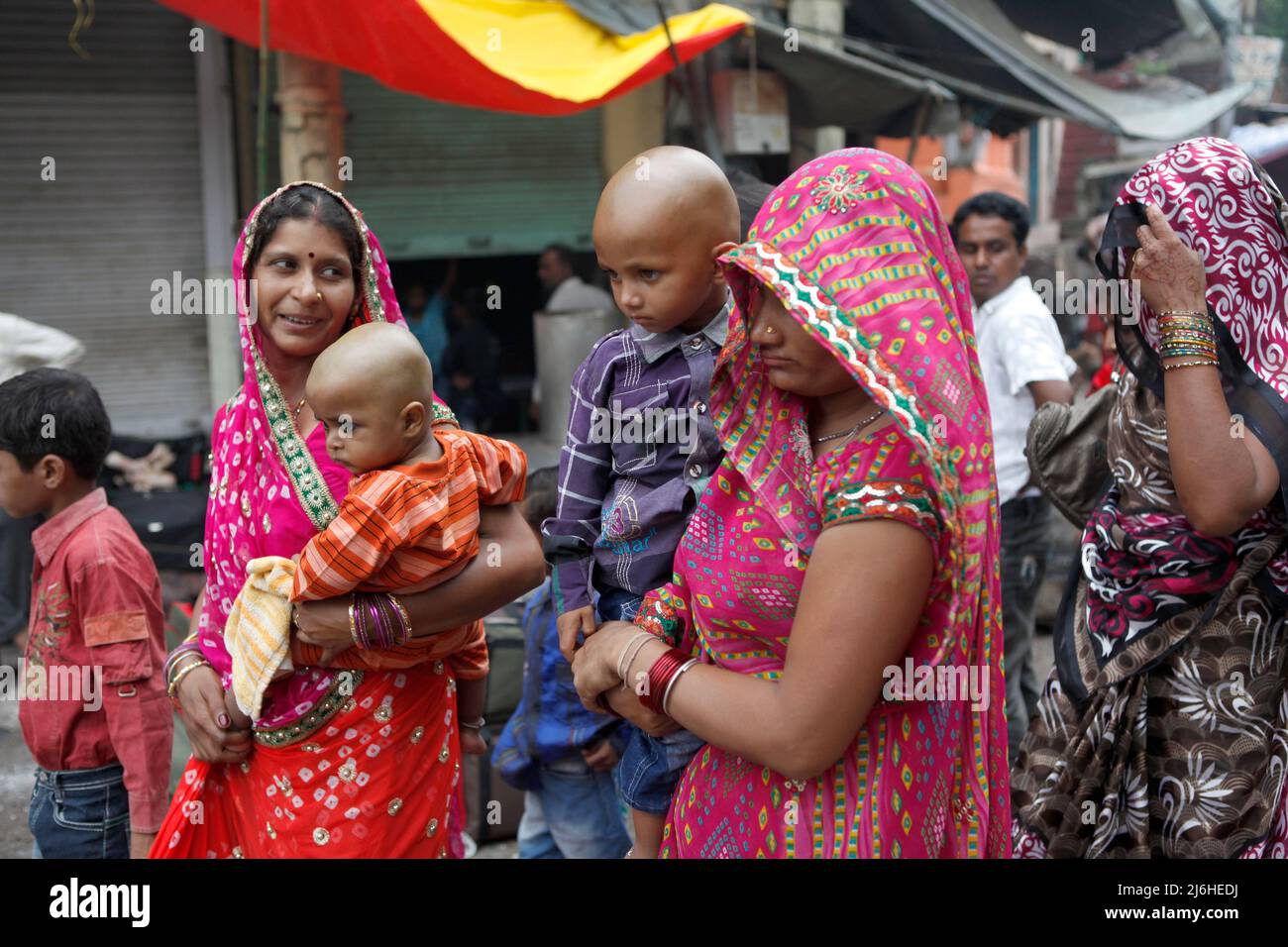 Frauen, die Babys tragen, gehen auf einer Straße in Varanasi, Uttar Pradesh, Indien. Stockfoto