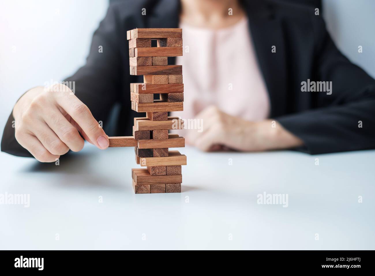 Geschäftsfrau Hand platzieren oder ziehen Holzblock auf dem Turm. Geschäftsplanung, Risikomanagement, Lösungs- und Strategiekonzepte Stockfoto