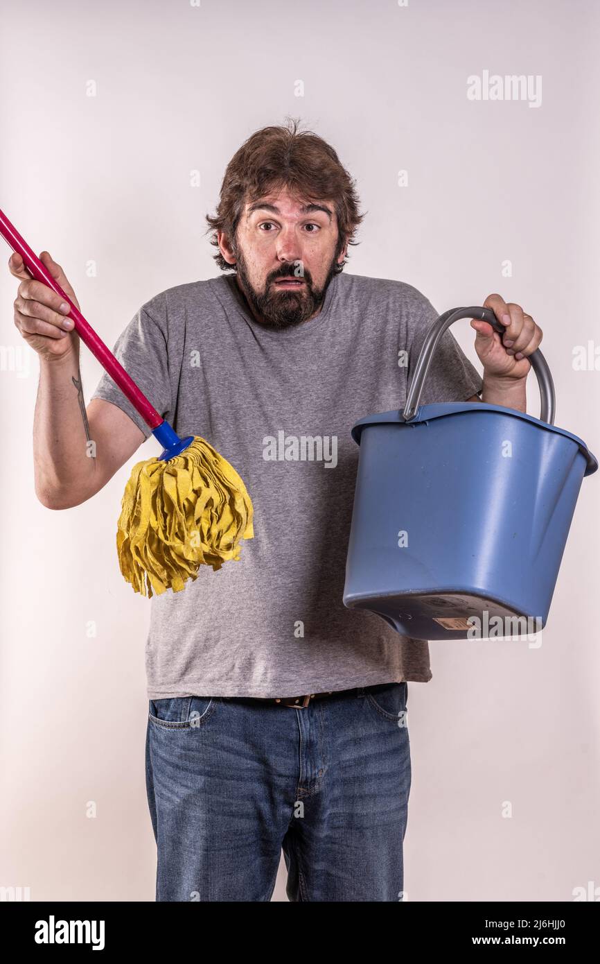 Mann mittleren Alters, kürzlich geschieden, mit Mopp und Eimer. Er weiß nicht, wie er Hausarbeit machen soll. Neuling. Konzept des Menschen in Not. Stockfoto