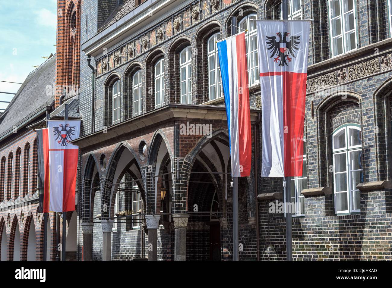 Eingang am historischen Rathaus von Lübeck mit der Flagge der hansestadt mit einem doppelköpfigen Adler und der Schleswig-holsteinischen Flagge mit Stockfoto