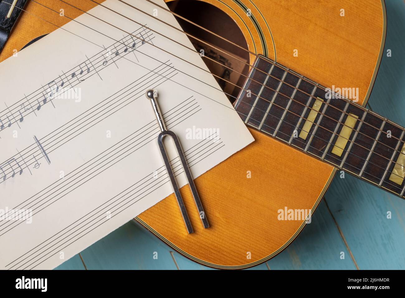 Musikaufnahme-Szene mit Gitarre, Notenblättern und Stimmgabel auf Holztisch, Nahaufnahme Stockfoto