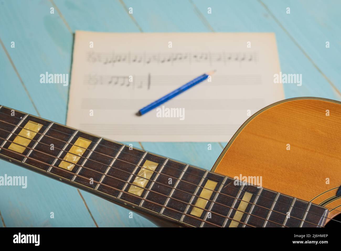 Musikaufnahme-Szene mit Gitarre, Notenblatt und Bleistift auf Holztisch Stockfoto