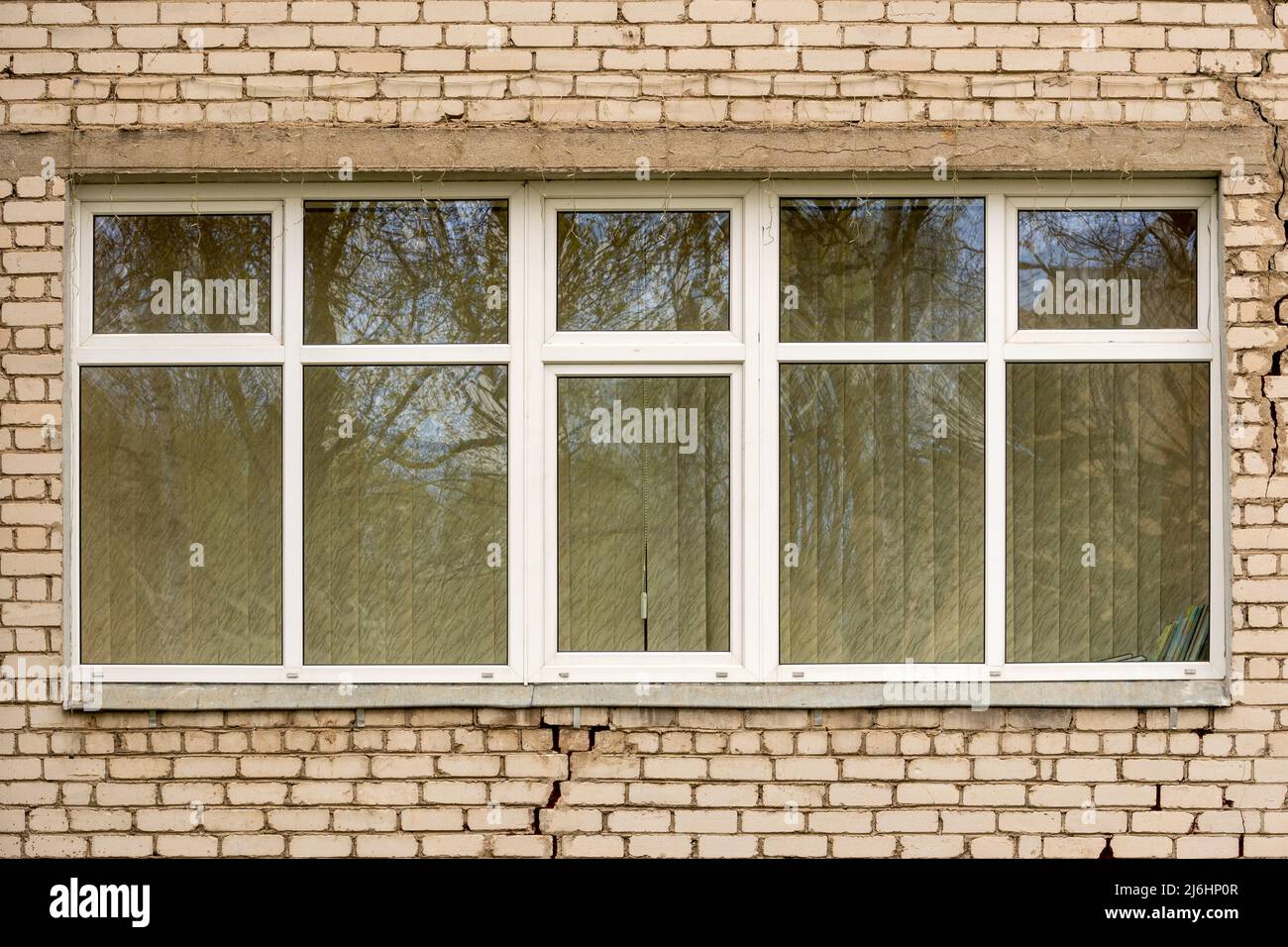 Rissige Ziegelwand und großes Fenster mit Vorhang Stockfoto