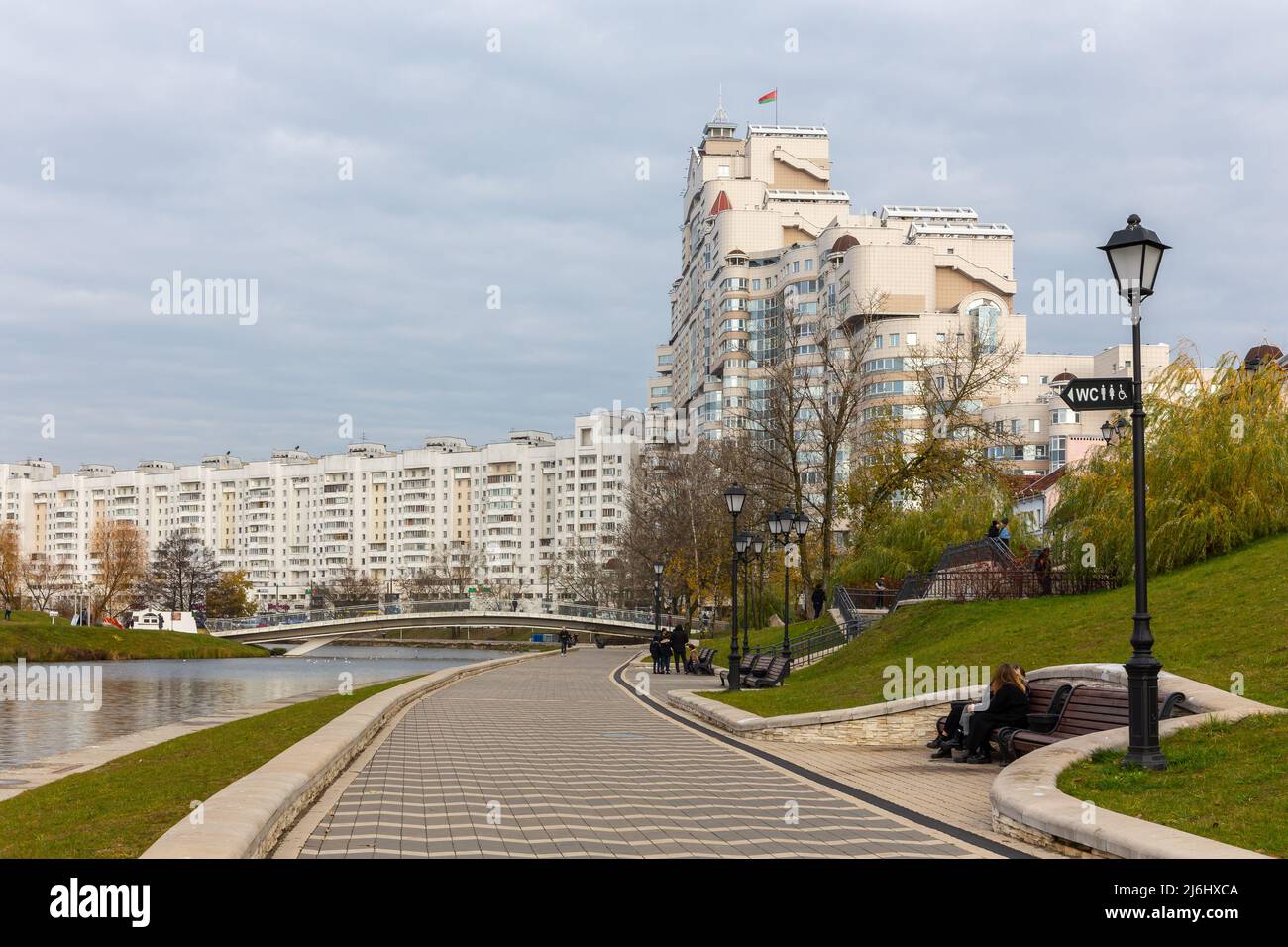 Minsk, Weißrussland, 04.11.21. Promenade am Fluss Svislach in Minsk mit Wohngebäude in massiver brutalistischer (sowjetischer) Architektur und Insel o Stockfoto