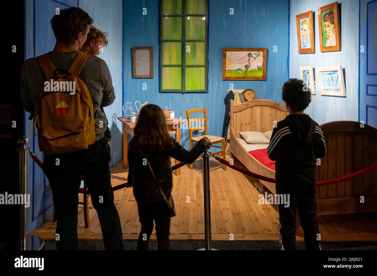 London Shoreditch, Großbritannien. 30. April 2022. Familie mit Kindern vor der Nachbildung von Bedroom in Arles bei Van Gogh die Immersive Experience Ausstellung Stockfoto