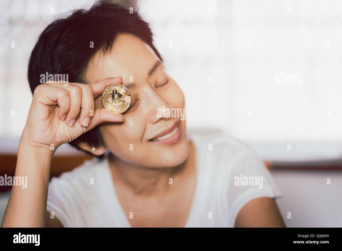 Erfolgreiche Frau mit Goldbitcoin in der Hand. Stockfoto
