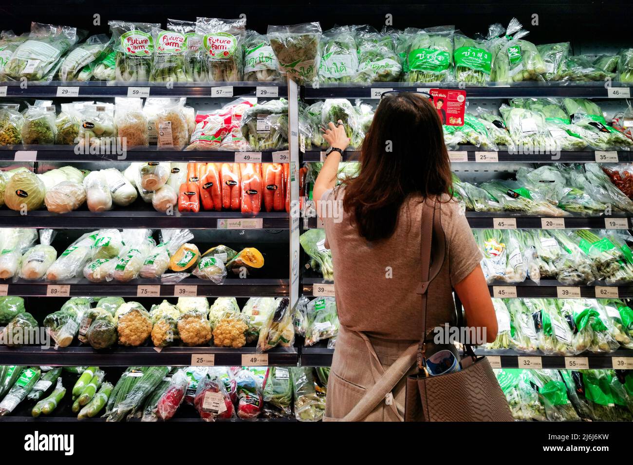 Bangkok, Thailand - 20. Januar 2022 : alleinstehende asiatische Frau einkaufen und kaufen Gemüse zu kochen Abendessen Essen nach der Arbeit im lokalen Supermarkt. Stockfoto