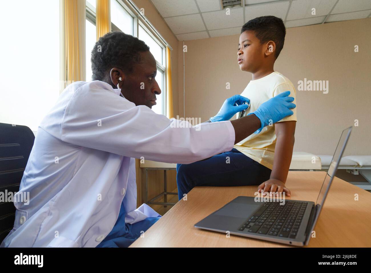 afroamerikanischer Mann Kinderarzt Arzt mit Stethoskop zur Untersuchung kleiner Junge von Krankheit im Büro im Krankenhaus. Medizinische und gesunde li Stockfoto