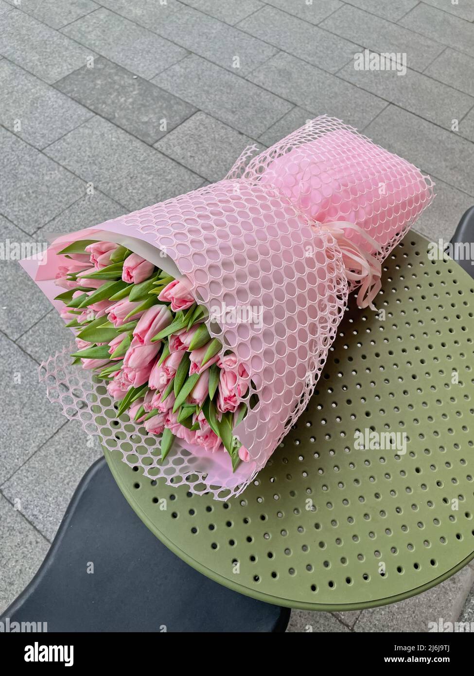 Ein Bukett aus rosa Tulpenin rosa Verpackung, die auf dem Kaffeetisch liegt. Stockfoto