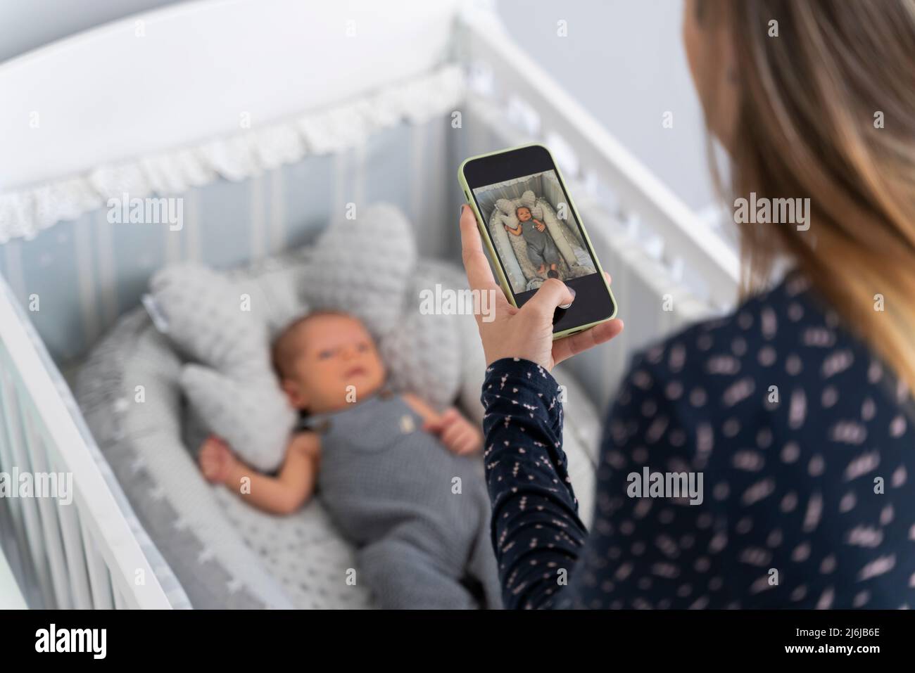Die junge Mutter fotografiert ihr neugeborenes Baby in der Wiege Stockfoto