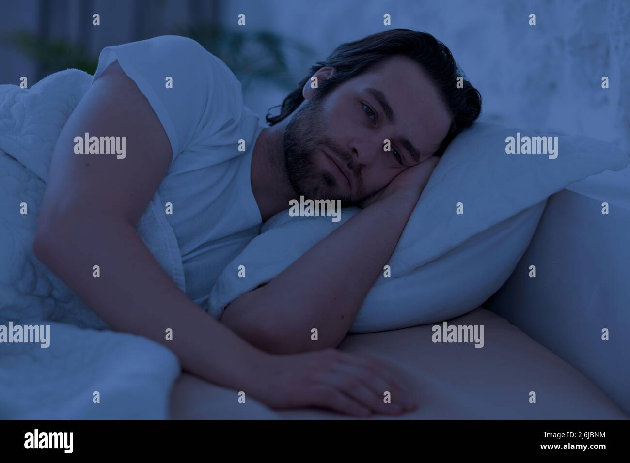 Deprimierter Mann kann nachts nicht schlafen und liegt allein im Bett Stockfoto