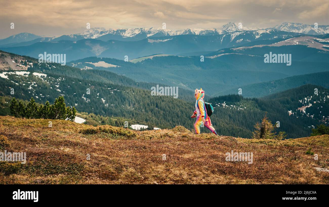 Frau im Einhorn-Kostüm reist in Frühlingsberge und genießt das Leben. Speichern und lieben Natur Konzept. Stockfoto