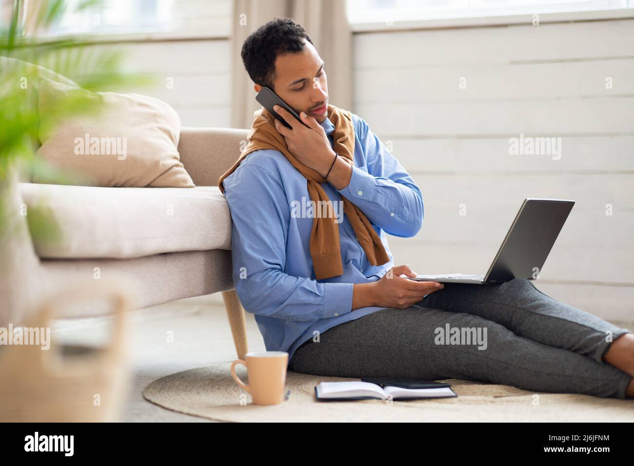 Arabischer Mann, der zu Hause telefoniert und arbeitet Stockfoto