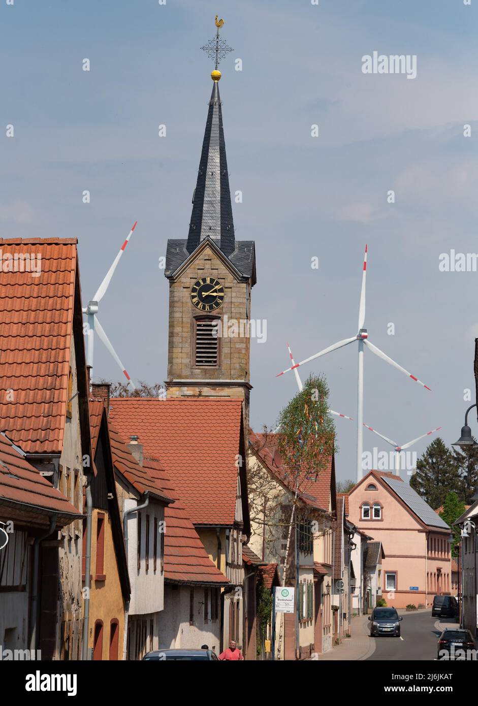 02. Mai 2022, Rheinland-Pfalz, Biedesheim: Windräder drehen sich hinter dem Kirchturm. Entlang der Autobahn A63 gibt es mehrere Windenergieanlagen. Foto: Boris Roessler/dpa Stockfoto