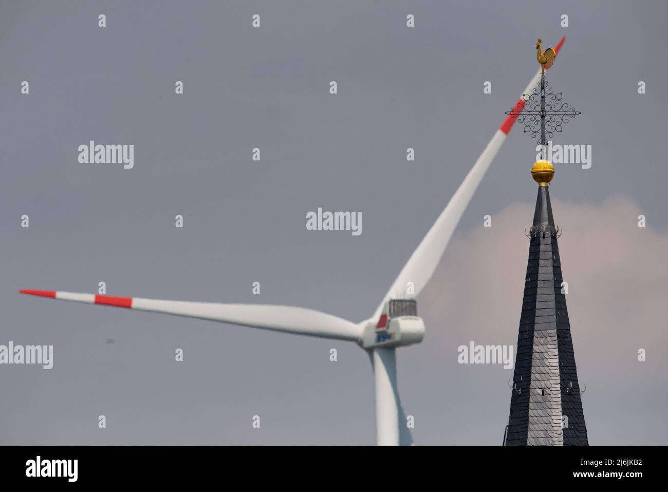 02. Mai 2022, Rheinland-Pfalz, Biedesheim: Hinter dem Kirchturm dreht sich eine Windturbine. Entlang der Autobahn A63 gibt es mehrere Windenergieanlagen. Foto: Boris Roessler/dpa Stockfoto