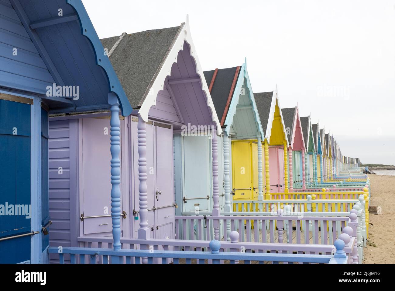 Bunt bemalte Strandhütten in einer Reihe in West Mersea, Mersea Island, Essex, Großbritannien Stockfoto