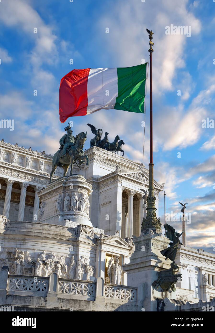 Schöner Blick auf ein Vittoriano - Denkmal zu Ehren von Viktor Emmanuel II. Mit einer italienischen Flagge gegen einen blauen Himmel am Abend. Rom, Italien Stockfoto