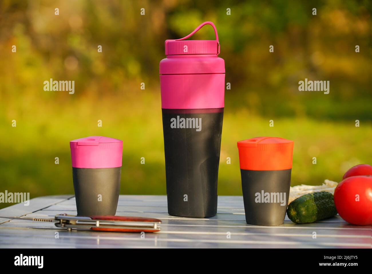 Ein Set Campingutensilien steht auf einem Klapptisch in der Natur. Flüssigbehälter für Touristen Stockfoto