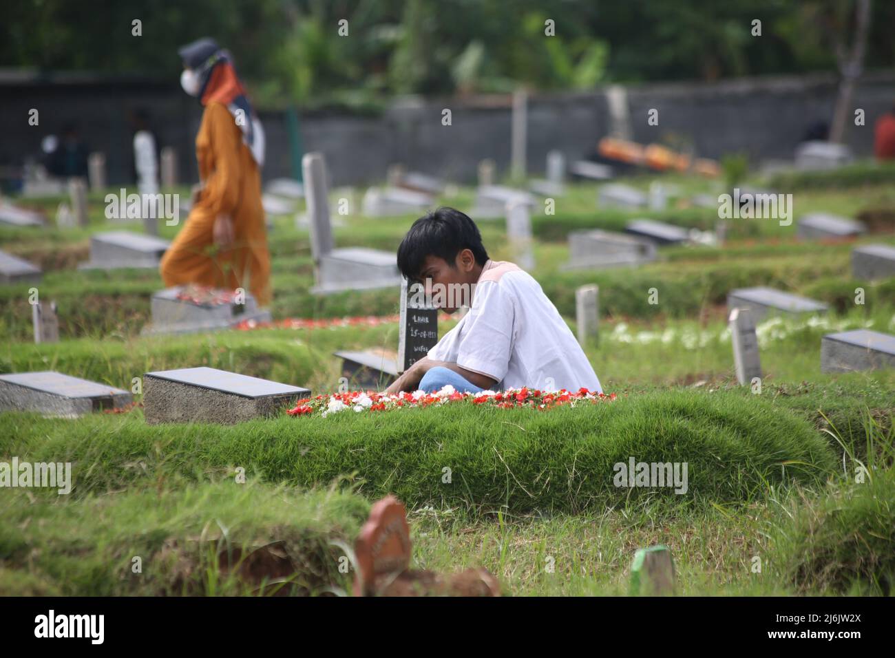 Die Traurigkeit eines Bewohners beim Beten, während er traurig während einer schweren Pilgerfahrt auf dem Covid-19 Friedhof, Rorotan, Cilincing, Jakarta, Indonesien, beklagt. Die diesjährige Eid al-Fitr-Feier wurde von einer Reihe von Muslimen genutzt, um Wallfahrten zu machen und für ihre Familien zu beten, die gemäß dem Covid-19-Protokoll begraben wurden. (Foto von Kuncoro Widyo Rumpoko/Pacific Press/Sipa USA) Stockfoto
