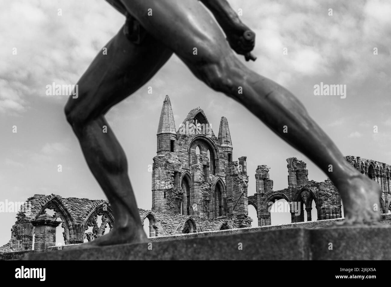 Whitby Abbey durch die Beine der Borghese Gladiator Statue in Whitby, Yorkshire, Großbritannien im April - in schwarz-weiß, monochrom Stockfoto