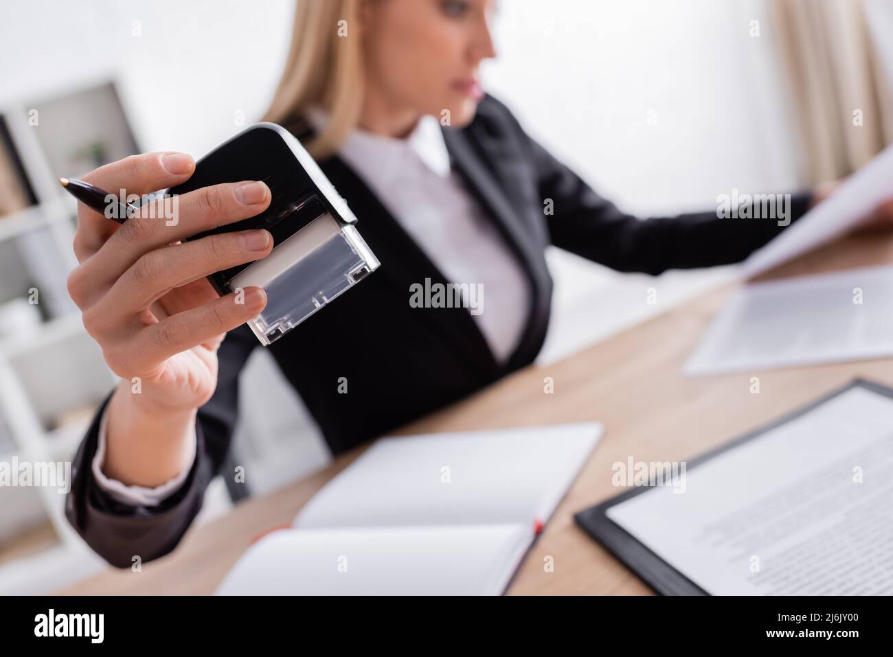 Selektiver Fokus der Büromarke in der Hand des Notars auf verschwommenem Hintergrund Stockfoto