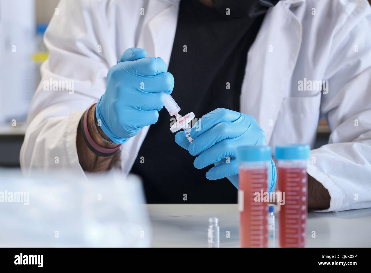 Wissenschaftler im weißen Labormantel filtert die Probe in das HPLC-Fläschchen. Stockfoto