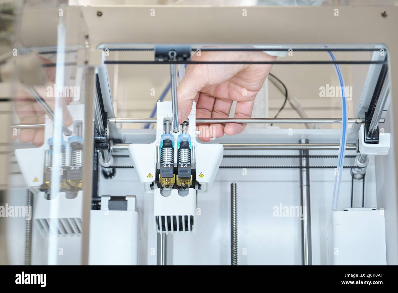 Nicht erkennbare Person, die die Düsen des 3D-Druckers aus Kunststoff wechselt. Stockfoto